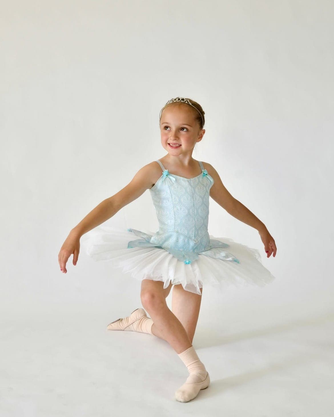 A young ballerina in a pale blue tutu posing in the studio