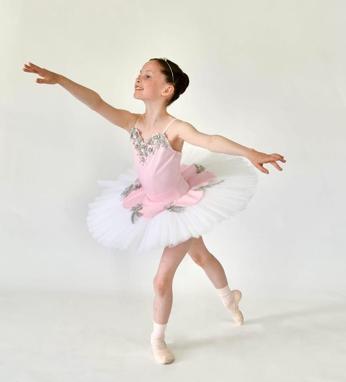 A young ballerina in a pink tutu posing in the studio