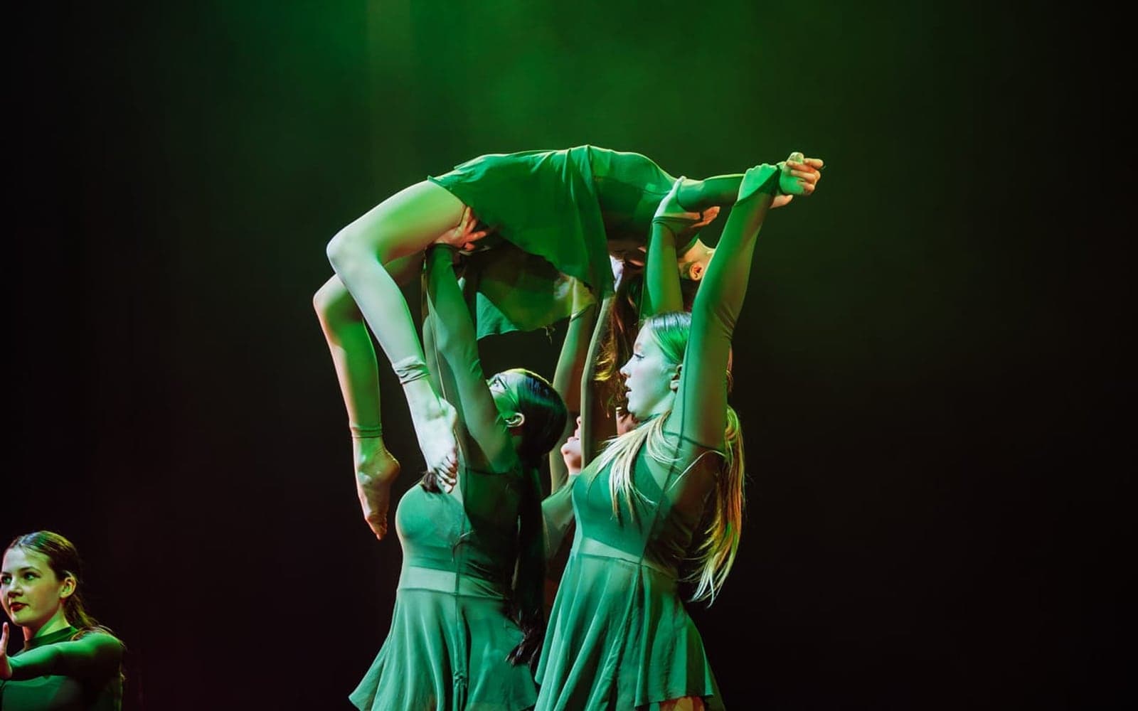 Contemporary dancers in a dramatic green-lit lift at the Geraldine Lamb Dance School