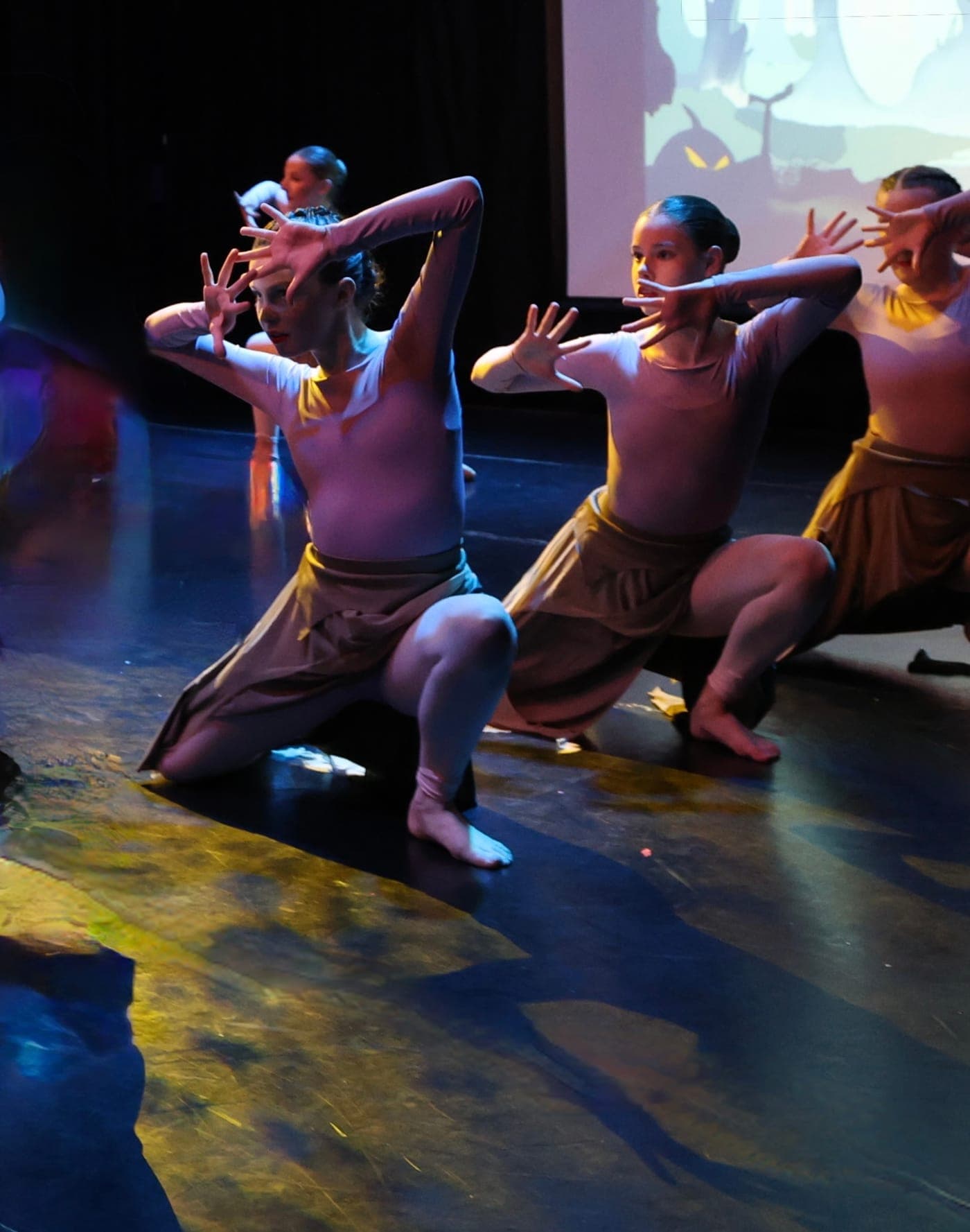 Contemporary dancers reaching upwards from a kneeling pose on stage