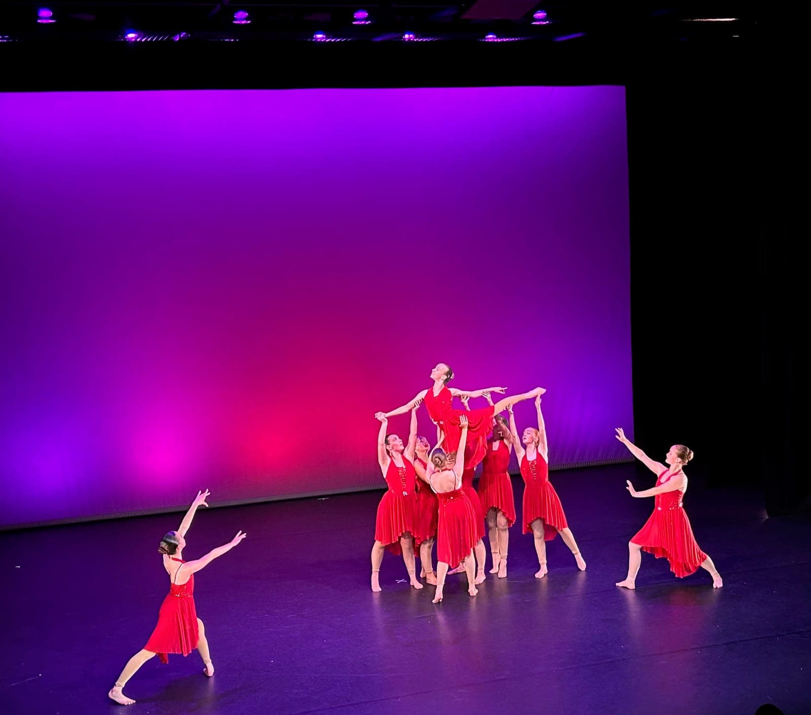 Contemporary dancers in red dresses performing a lift