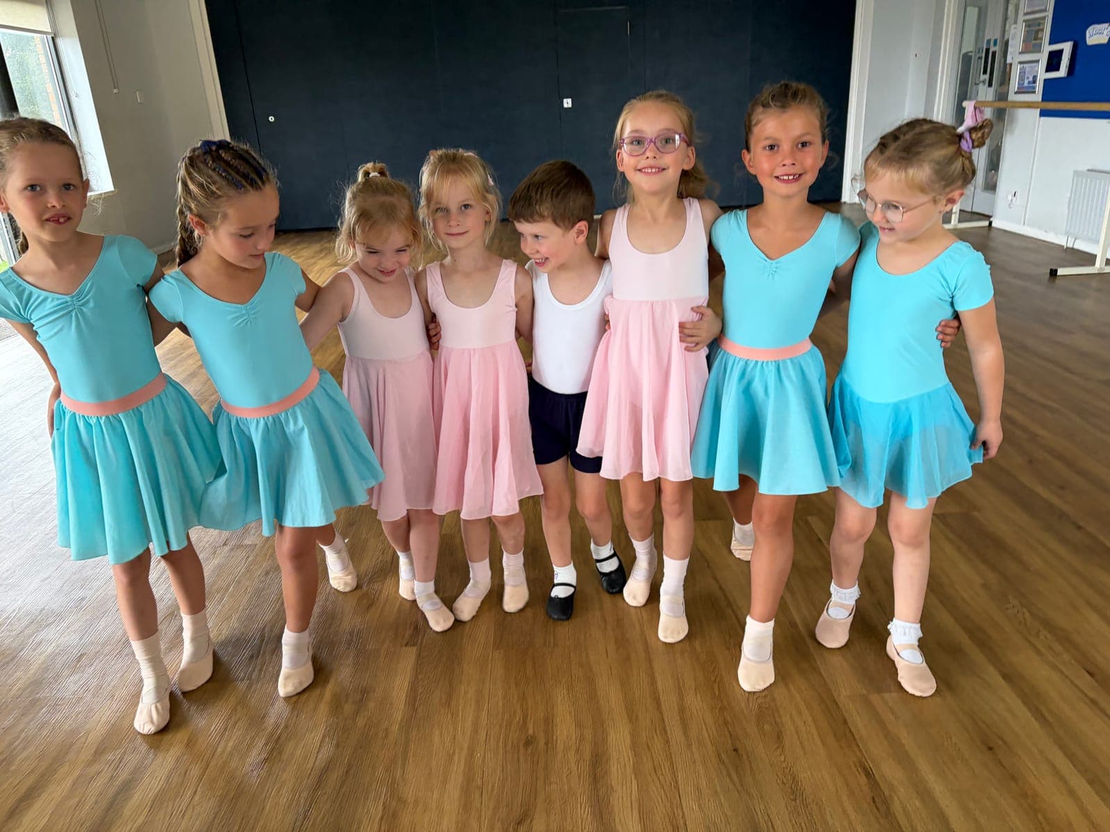 Young dancers smiling arm in arm in ballet class at GLDS