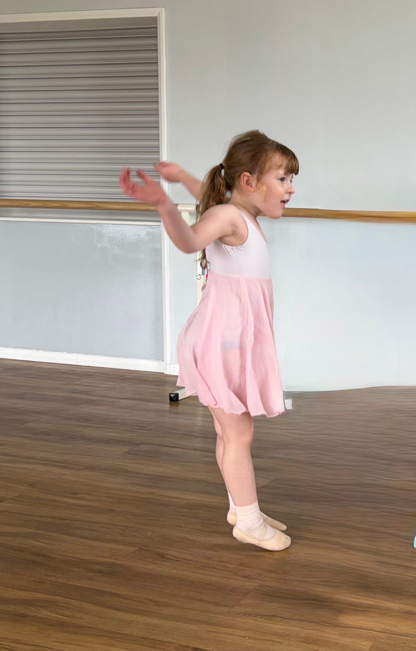 A pre-school dancer in a pink ballet dress mid twirl
