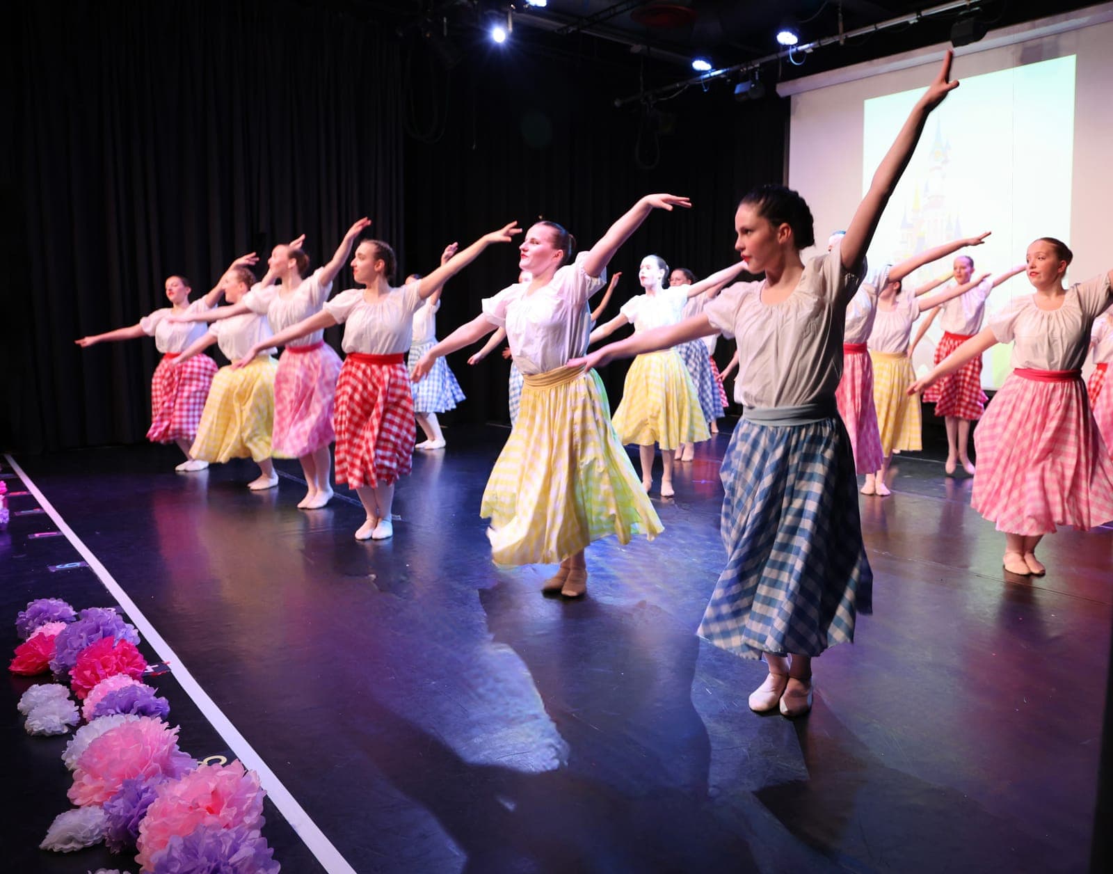 Dancers in gingham skirts and white blouses on stage