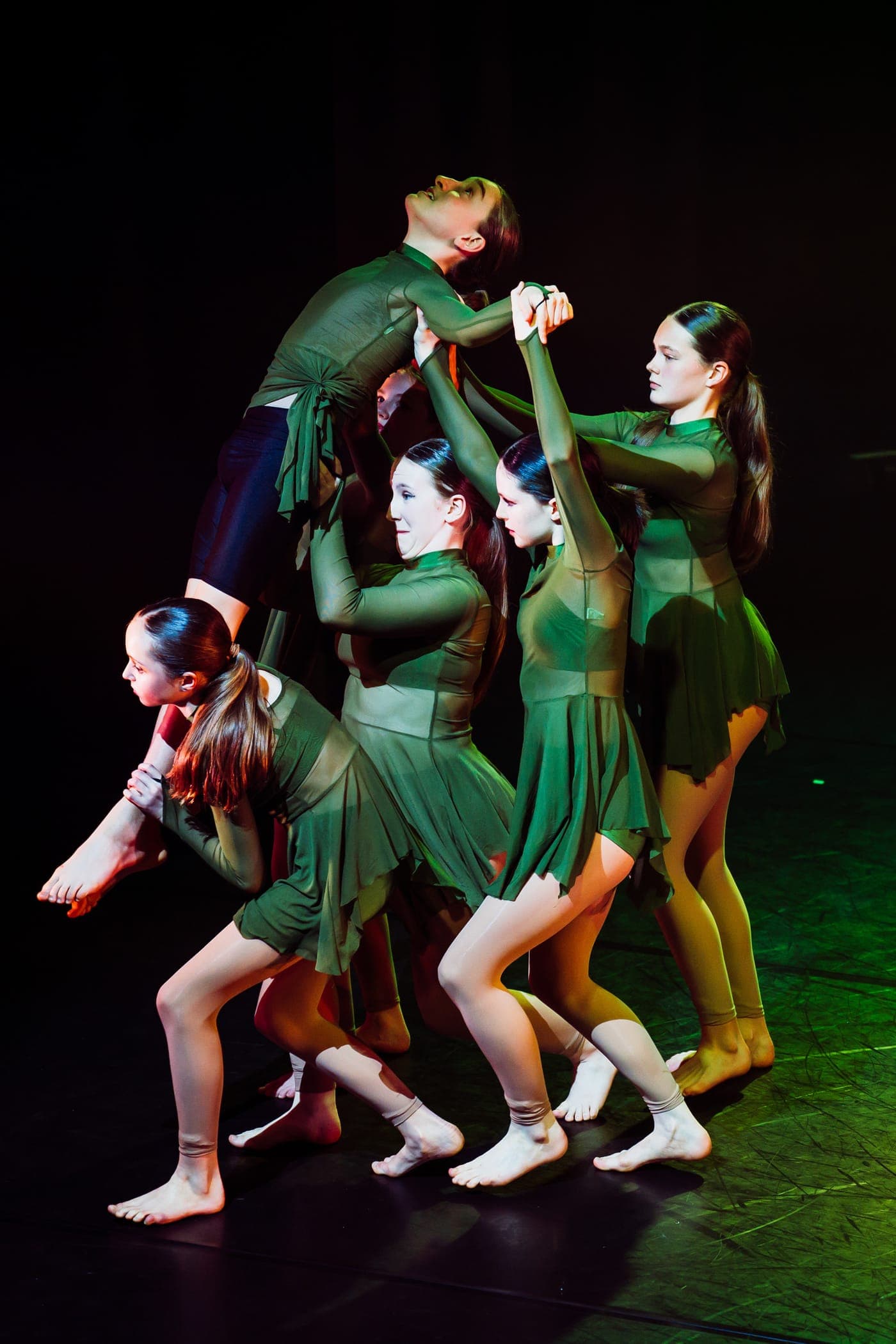 Geraldine Lamb dancers in green costumes holding a group balance on stage