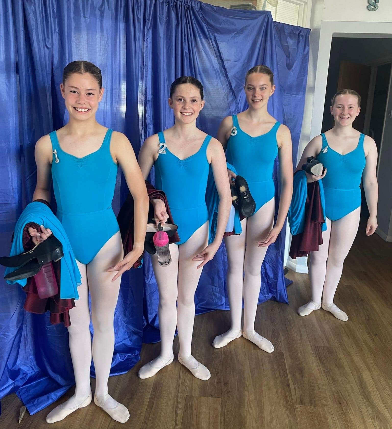 Four ballet students in blue leotards in the studio