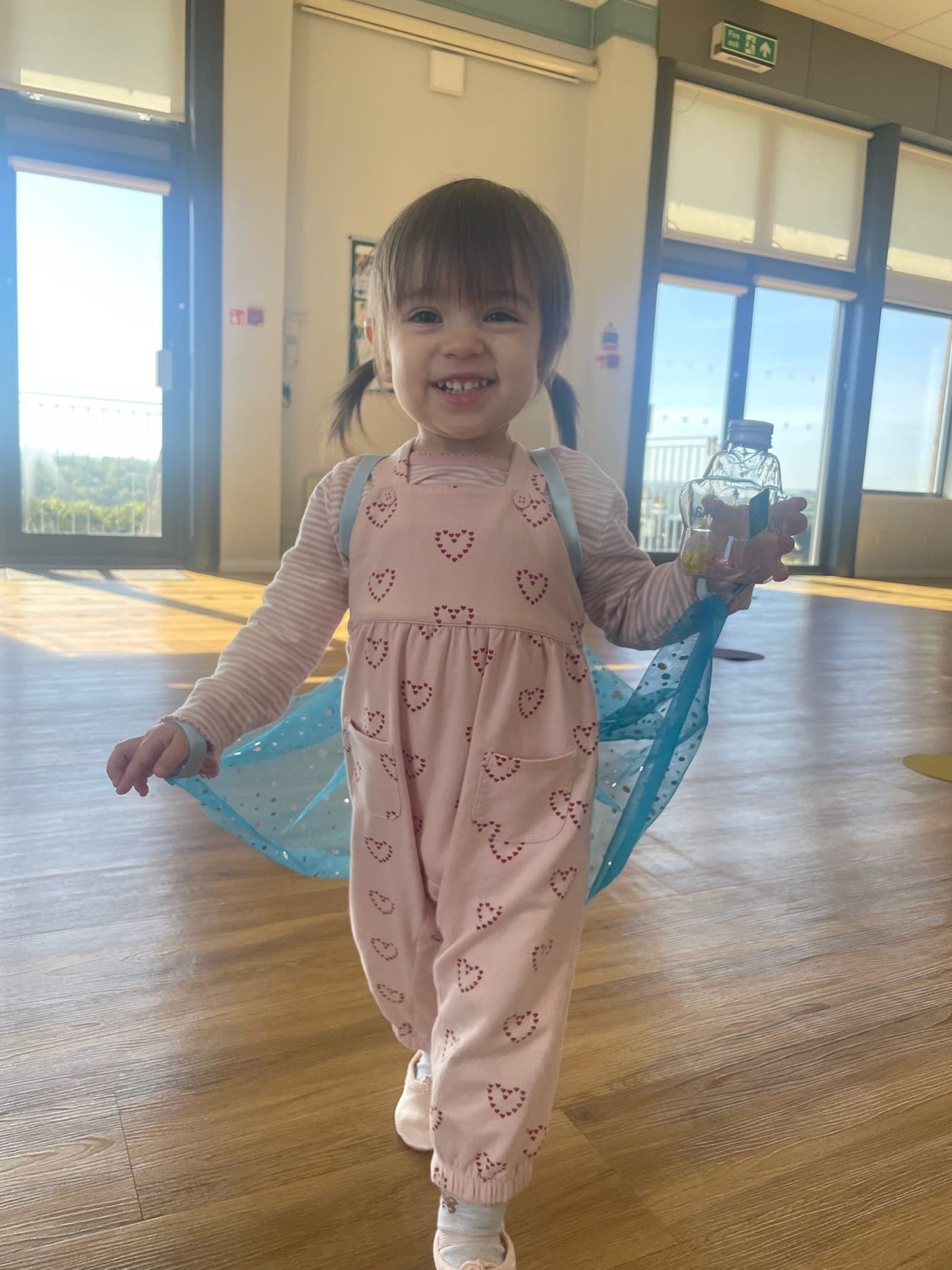 A smiling toddler with a blue scarf arriving in the studio