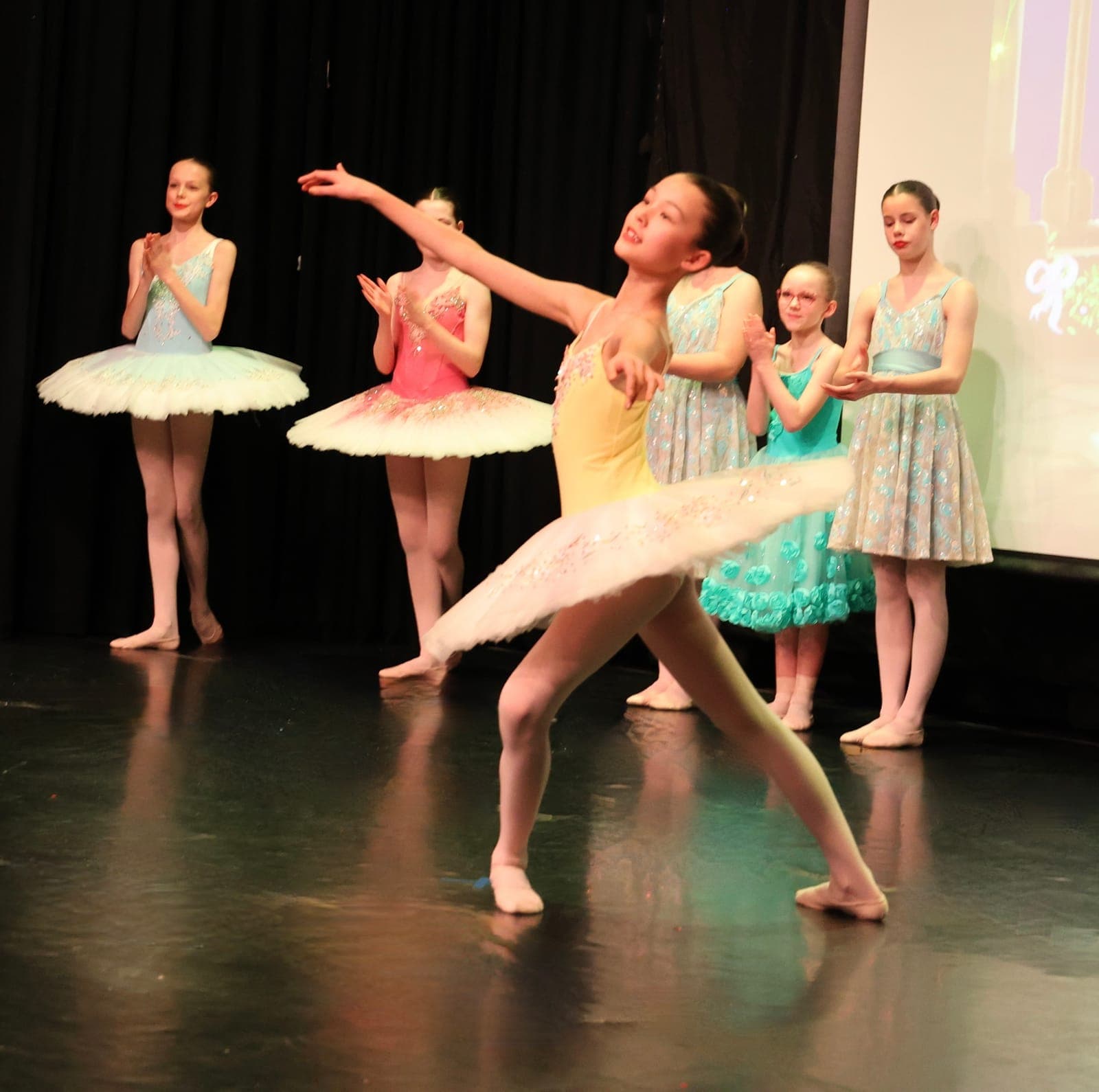 Young ballerina in a yellow tutu with the company behind